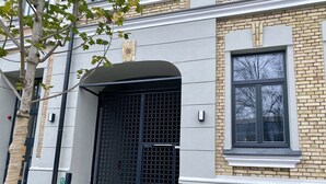 Ein Gebäude mit einem schwarzen Tor, einem Fenster und einem Baum davor.