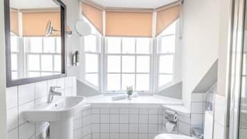 A modern bathroom with a sink, mirror, and bathtub.