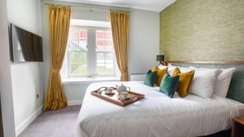 Un dormitorio con cama, cortinas, una ventana y una bandeja con juego de té.