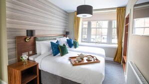 Une chambre d’hôtel avec un grand lit, une table de chevet avec une lampe, une fenêtre avec des rideaux et une vue sur l’extérieur.