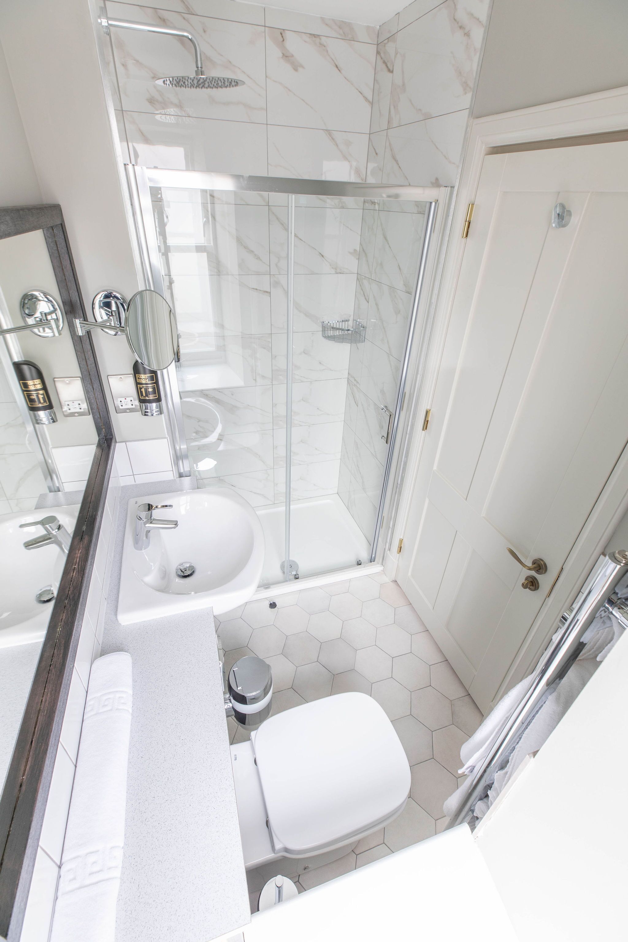A modern bathroom with a glass-enclosed shower, a white sink, and a toilet.