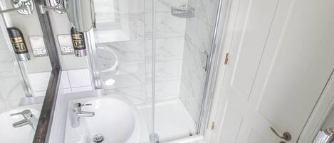 A modern bathroom with a glass-enclosed shower, a white sink, and a toilet.