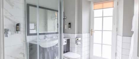 A modern bathroom with a glass shower enclosure, a white sink, and a toilet.