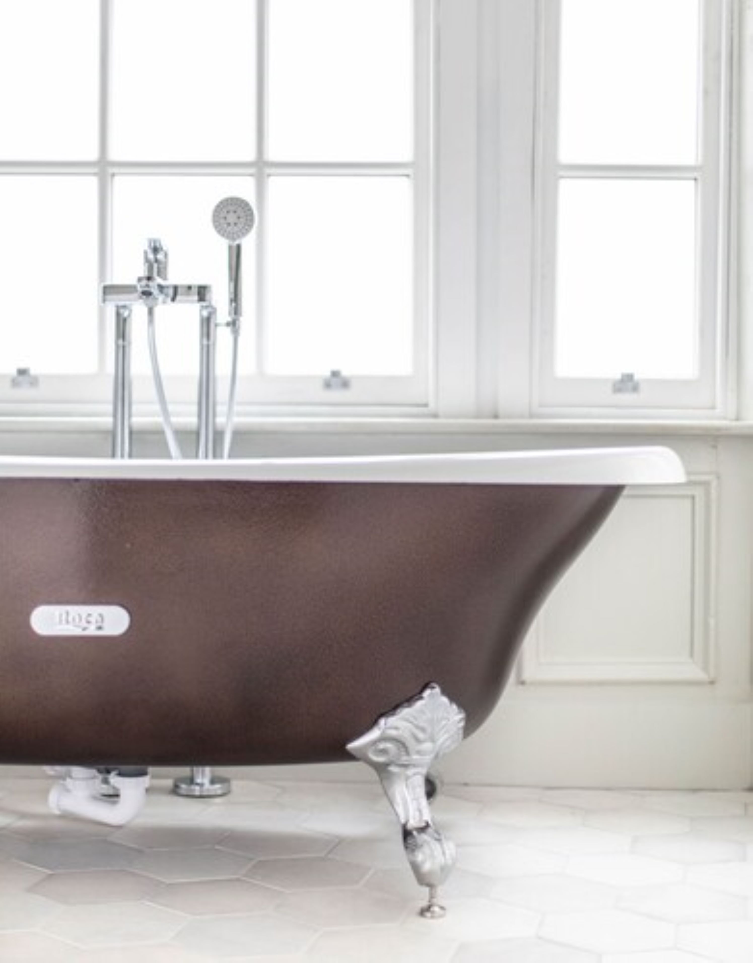 A bathroom with a freestanding bathtub, a window, and a tiled floor.
