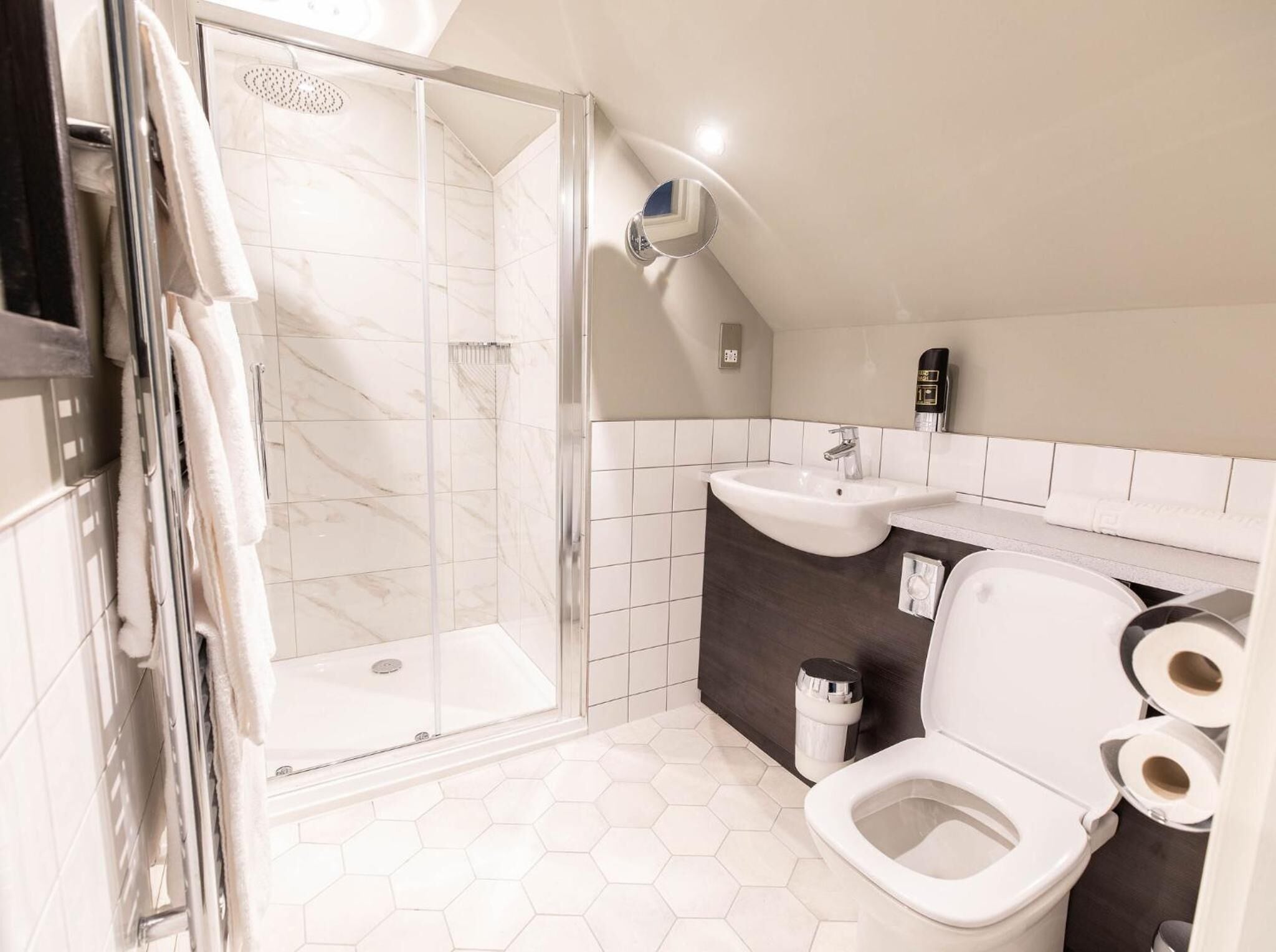 Un baño moderno con ducha envuelta en vidrio, lavamanos e inodoro.