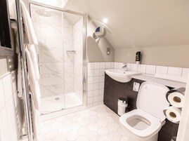 Un baño moderno con ducha envuelta en vidrio, lavamanos e inodoro.