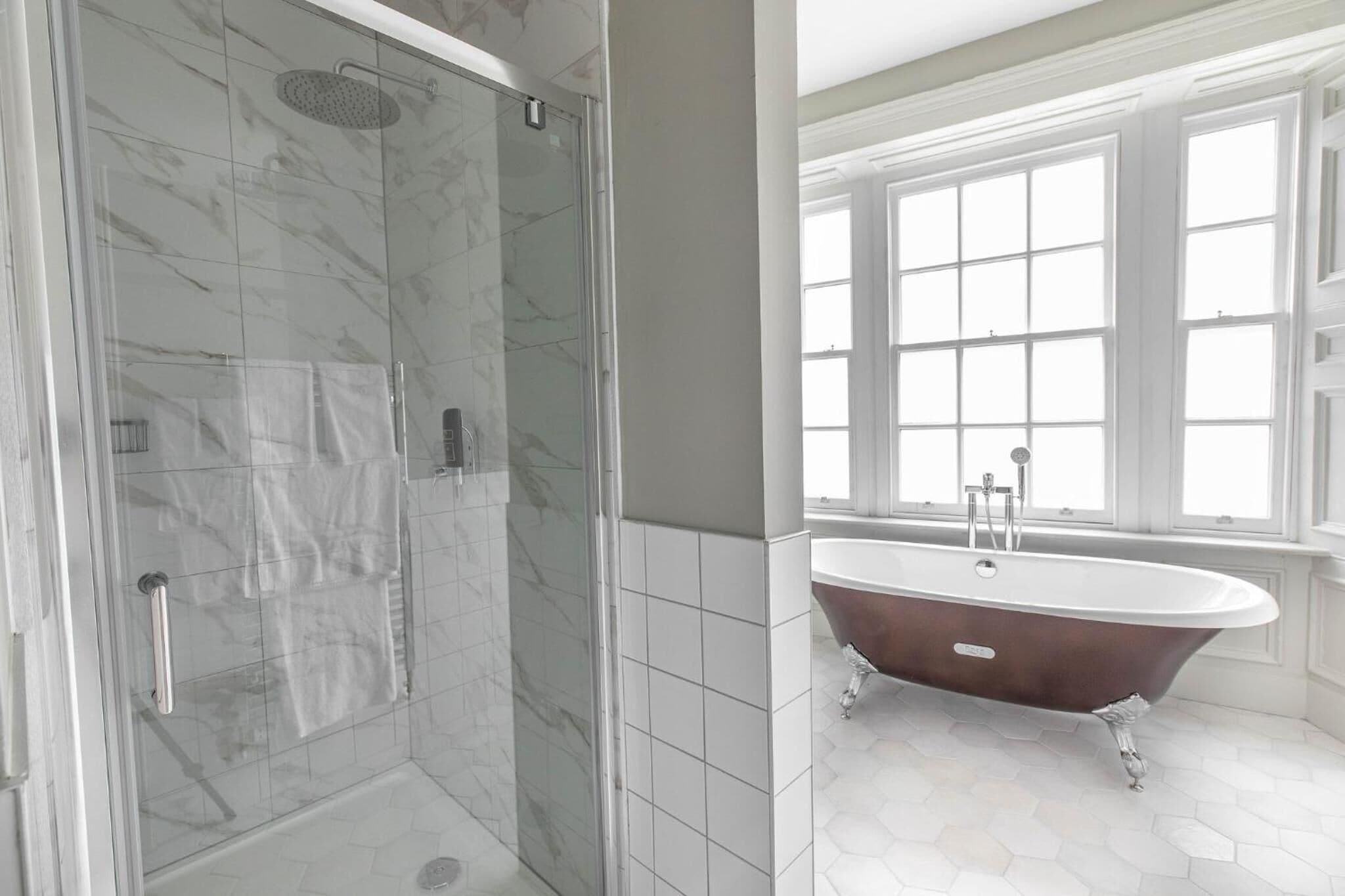 A bathroom with a glass-enclosed shower, a freestanding bathtub, and a large window providing natural light.
