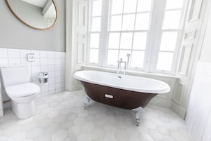 Un baño con una bañera independiente, inodoro y ventana con vistas.