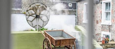 A rustic outdoor setting with a wooden cart and a large, circular, glass-like structure emitting steam.