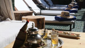 Una mesa con una tetera, vasos y una bandeja de pasteles.