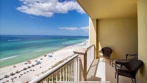 A balcony with a view of a beach, a pier, and clear skies.