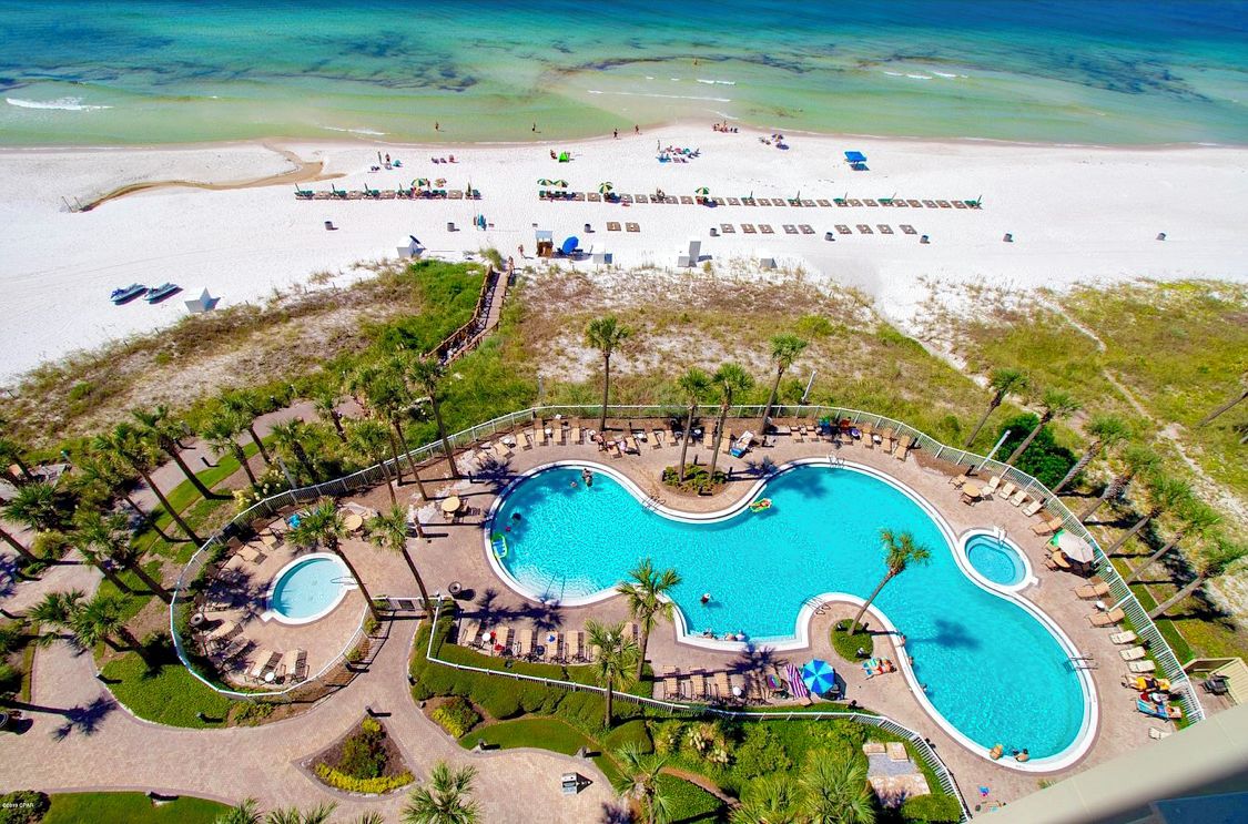 A resort with a large central pool, multiple smaller pools, and a beach area.