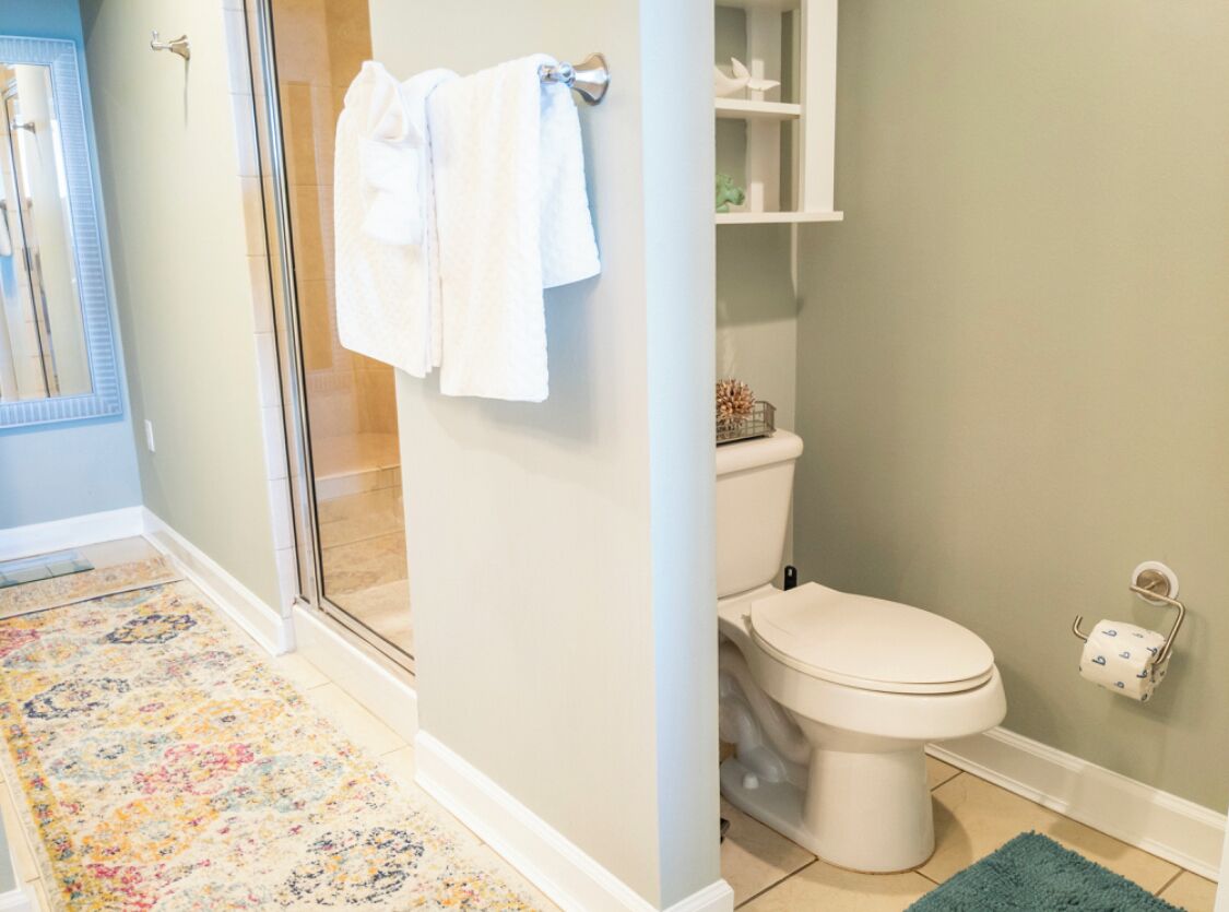 A bathroom with a toilet, a shower, and a sink.