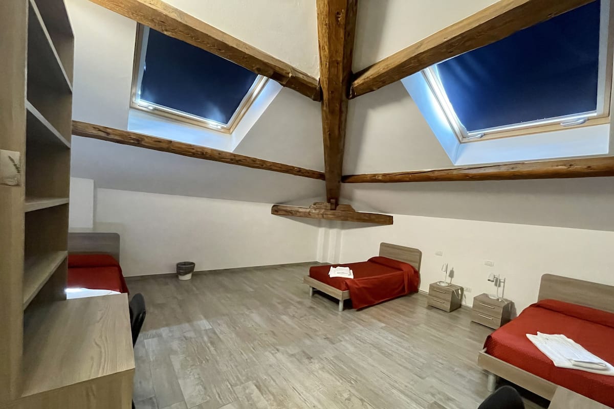 A room with two beds, a wooden ceiling, and skylights.