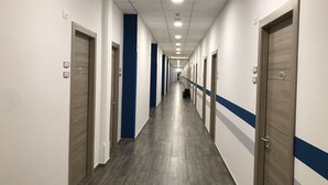 A long, narrow hotel corridor with doors on both sides, numbered signs, and a blue stripe on the walls. - Casa per ferie Don Bosco (Verona)