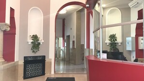 A reception area with a red desk, a black mat with 'istituto don bosco' text, and a hallway leading to another room. - Casa per ferie Don Bosco (Verona)