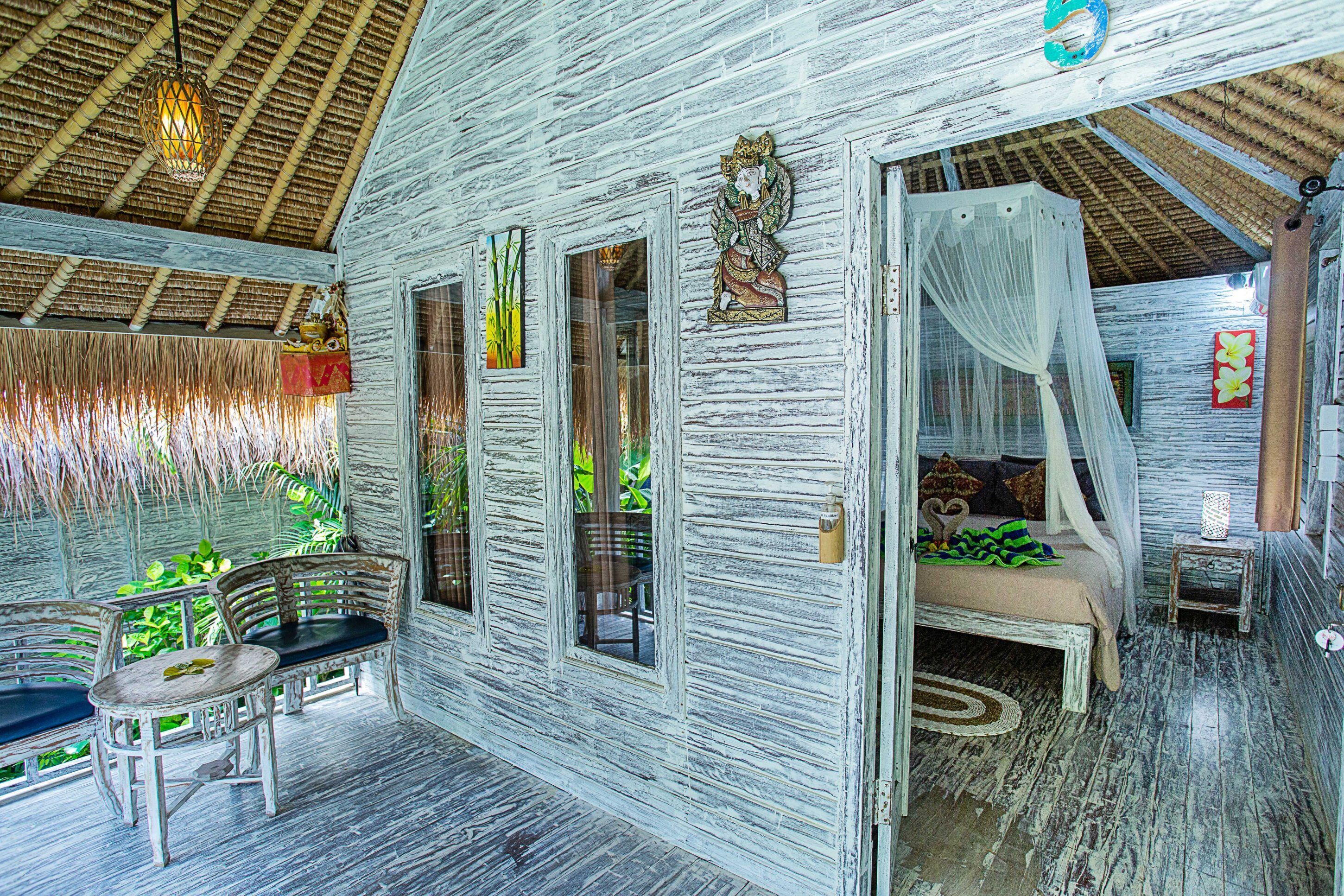 A rustic wooden cabin with a bed, a chair, and a table.