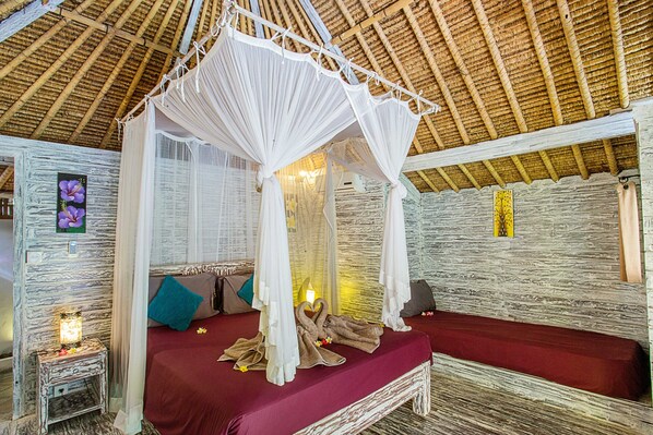 A room with a four-poster bed, a small bedside table, and a wall-mounted lamp. - Naturale Villa (Lembongan Island)