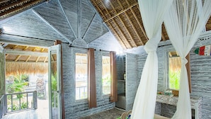 A room with a stone wall, a wooden ceiling, and a bed with a striped blanket. - Naturale Villa (Lembongan Island)