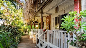 A wooden deck with a railing, surrounded by lush tropical plants. - Naturale Villa (Lembongan Island)
