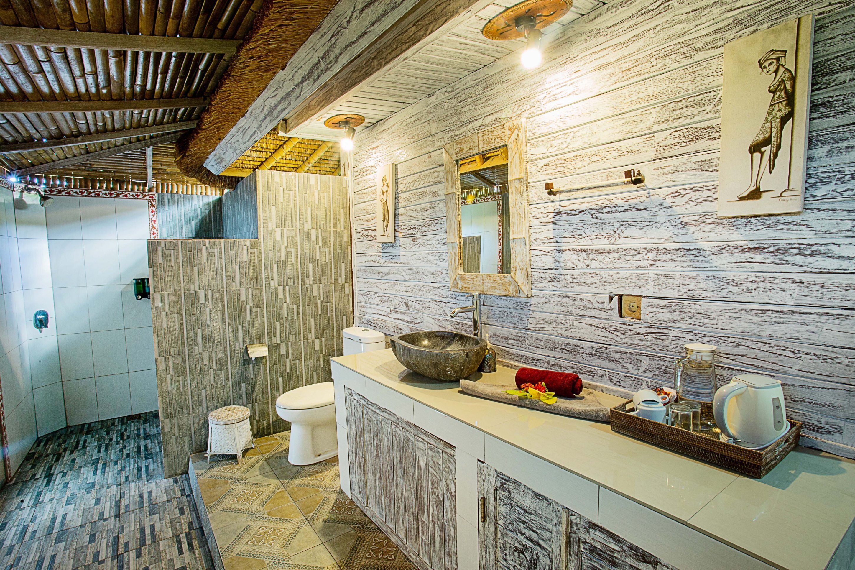 A modern bathroom with a stone sink, a large mirror, and a shower area.