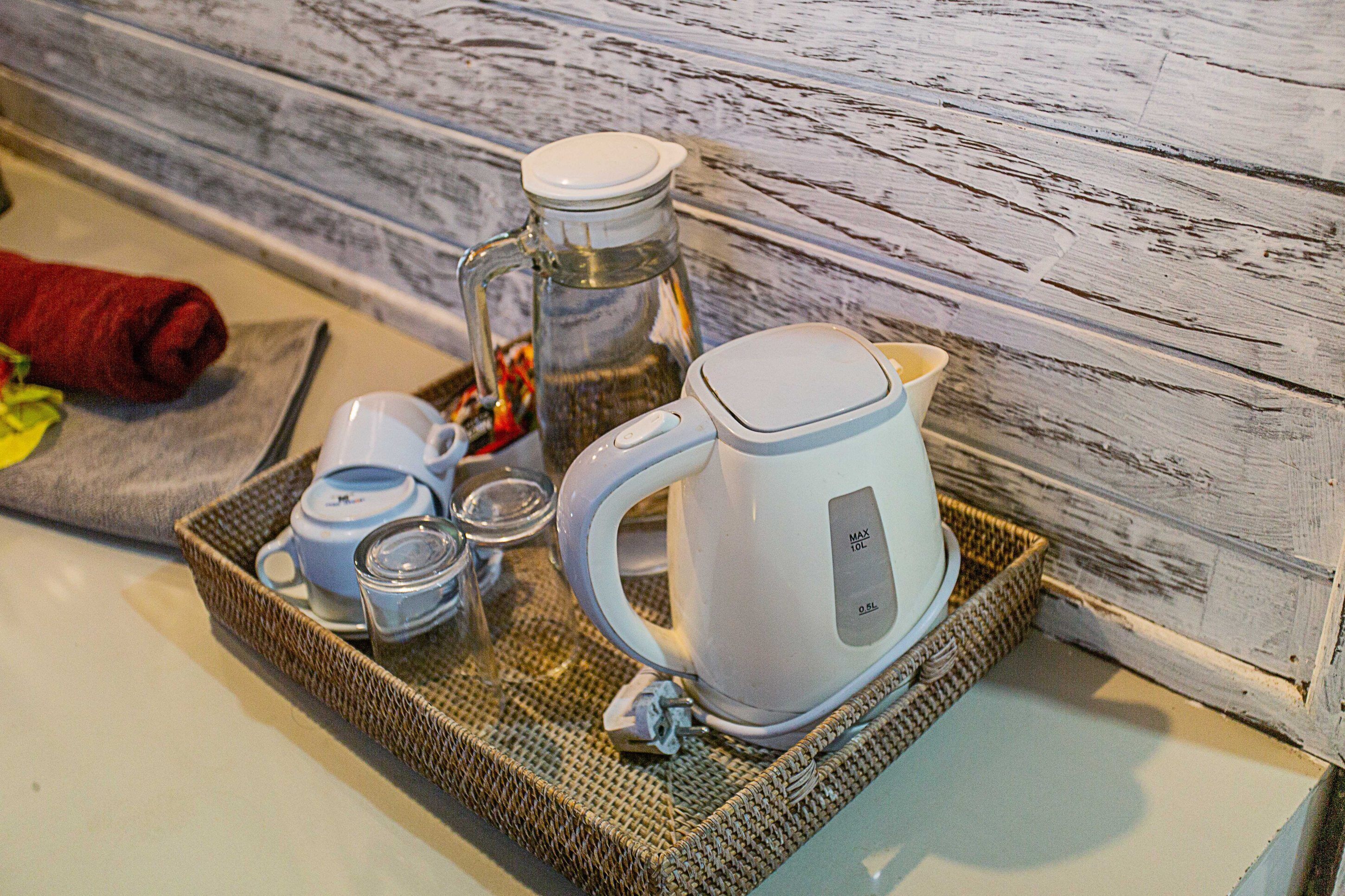 A tray with a coffee maker, a glass carafe, and a mug on a woven tray.