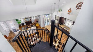 A spacious loft with a high ceiling, a staircase, and a kitchen area.