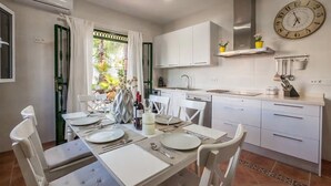A modern kitchen with white cabinets, a built-in oven, and a clock on the wall. - Villa del Manzano, Complete villa with pool just 15 minutes from Seville (Villanueva del Ariscal)