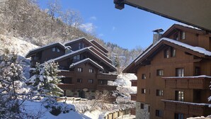 A wooden chalet-style building with multiple balconies, surrounded by snow-covered trees and a clear sky. - Charming 3 rooms 3* residence Swimming pool, sauna, gym in Méribel Village (Méribel Village)