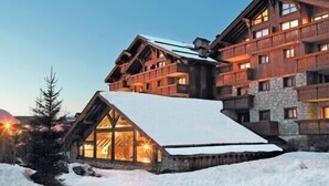 A multi-story wooden lodge with a snow-covered roof and large windows. - Charming 3 rooms 3* residence Swimming pool, sauna, gym in Méribel Village (Méribel Village)