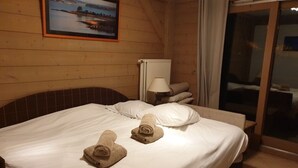 A hotel room with a bed, a radiator, a lamp, and a view of the outside. - Charming 3 rooms 3* residence Swimming pool, sauna, gym in Méribel Village (Méribel Village)