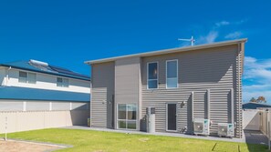 A two-story residential building with a flat roof, a satellite dish, and an air conditioning unit.