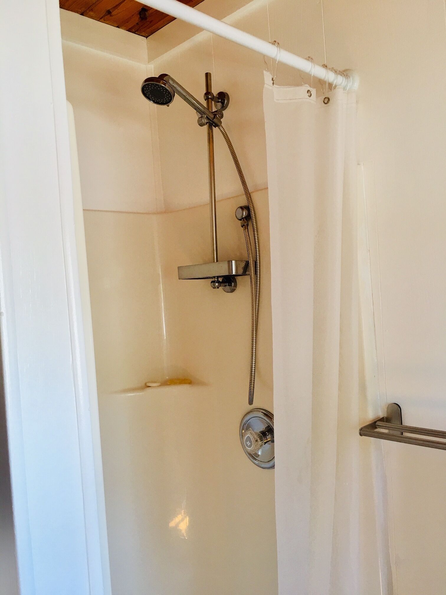 A shower with a handheld showerhead and a wall-mounted faucet.