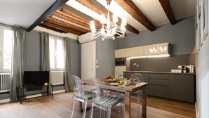 Cozinha moderna com forno embutido e área de jantar com mesa de madeira e cadeiras transparentes.