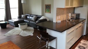Ein modernes Wohnzimmer mit einer Couch, einem Couchtisch und einem Essbereich mit Küchenzeile und Stühlen.