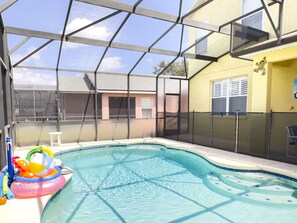 An indoor swimming pool with a glass enclosure, a slide, and inflatable toys.
