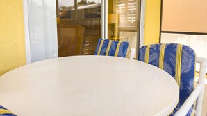 Una mesa redonda con sillas a rayas azules y amarillas, un vidrio que da al exterior y una pared amarilla.