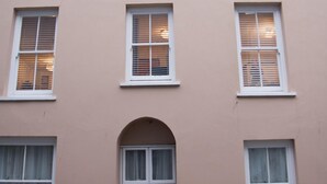 A building with multiple windows, a central arched doorway, and a pink facade. - Ideal location for enjoying all of Tenby's attractions (Tenby)