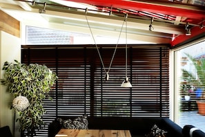 Una habitación con pared de listones de madera, una lámpara colgante y una planta en maceta.