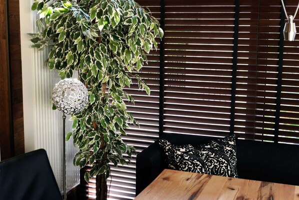 Une pièce avec une table en bois, des coussins aux motifs noir et blanc, une plante suspendue et un luminaire décoratif.