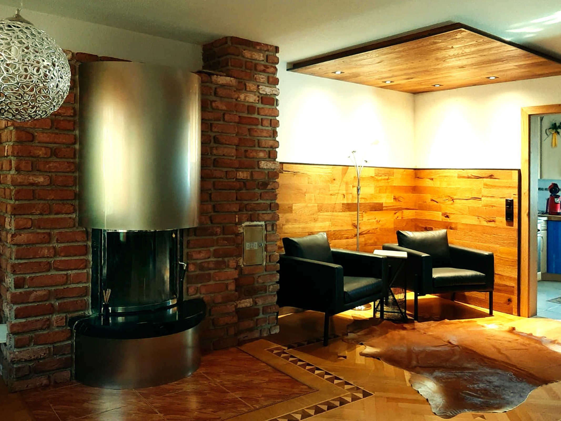 Ein modernes Wohnzimmer mit Kamin, Backsteinwand, Holzboden und Ledermöbeln.