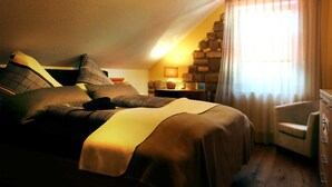 Een knus slaapkamer met een bed, kussens, een stoel, een dressoir en een lamp.