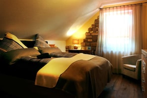 Une chambre confortable avec un lit, des oreillers, une chaise, une commode et une lampe.