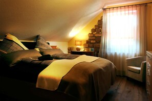 Une chambre confortable avec un lit, des oreillers, une chaise, une commode et une lampe.