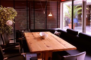 Une table en bois, un saladier, des chaises noires, un canapé et une plante en pot.