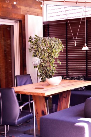 Una mesa de madera con sillas, una planta en maceta y una lámpara colgante.