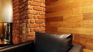 Een kamer met een bakstenen muur, een houten wandpaneel en een leren fauteuil.