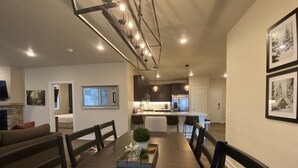 A modern living room with a dining table, a kitchen in the background, and a large window. - Spacious New Condo - Beautiful Views in the Heart of  Dillon. License# 651848101 (Dillon)
