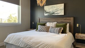 A bedroom with a large bed, a chandelier, a painting, and a window. - Spacious New Condo - Beautiful Views in the Heart of  Dillon. License# 651848101 (Dillon)