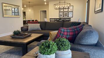 A modern living room with a sectional sofa, a wooden coffee table, and two potted plants.